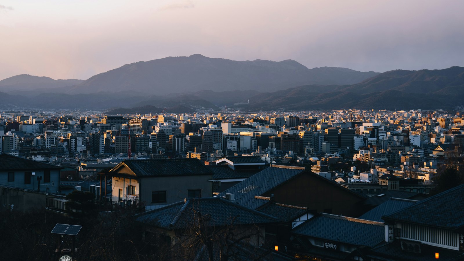 Ciudad japonesa y montañas al atardecer, representando la base de Pentos en Japón.